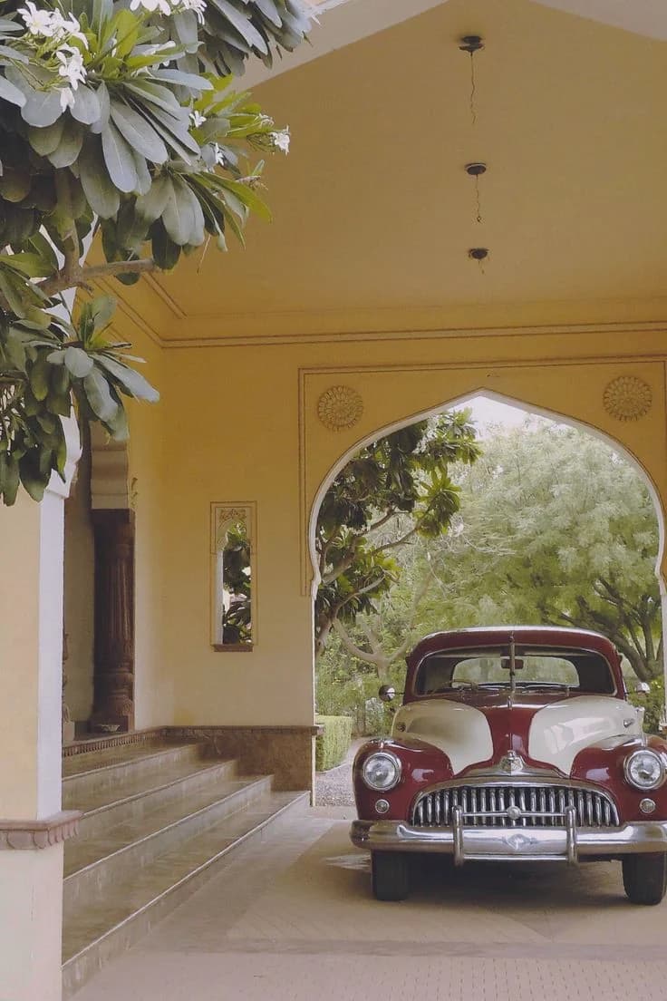 A yellow palace archway with a vintage car parked beneath it