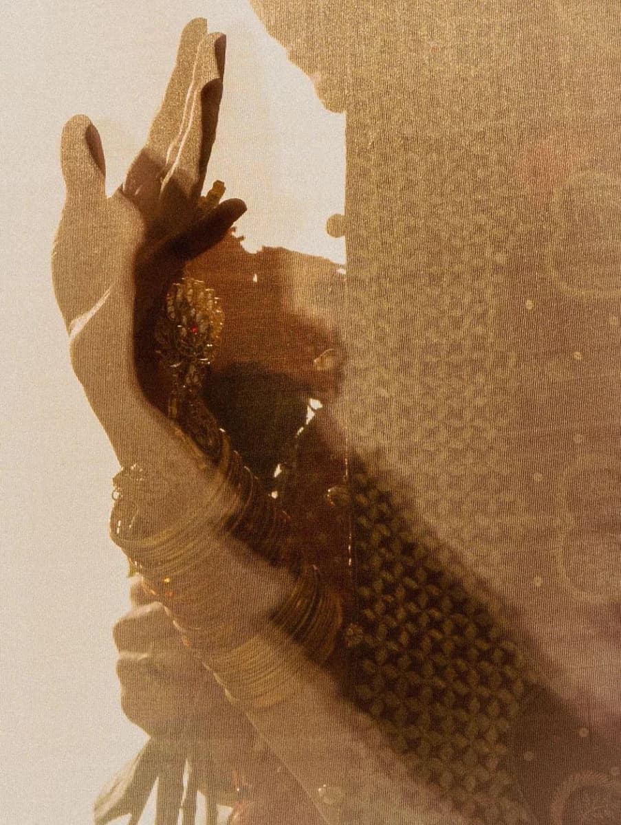 A henna-painted hand resting against gold