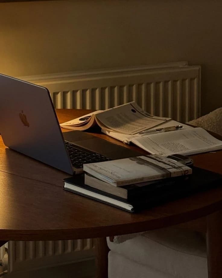 A desk at night with papers and a lamp